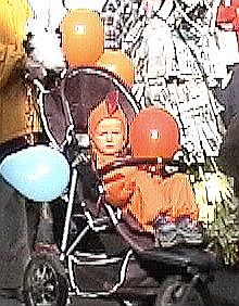child in buggy with orange balloon